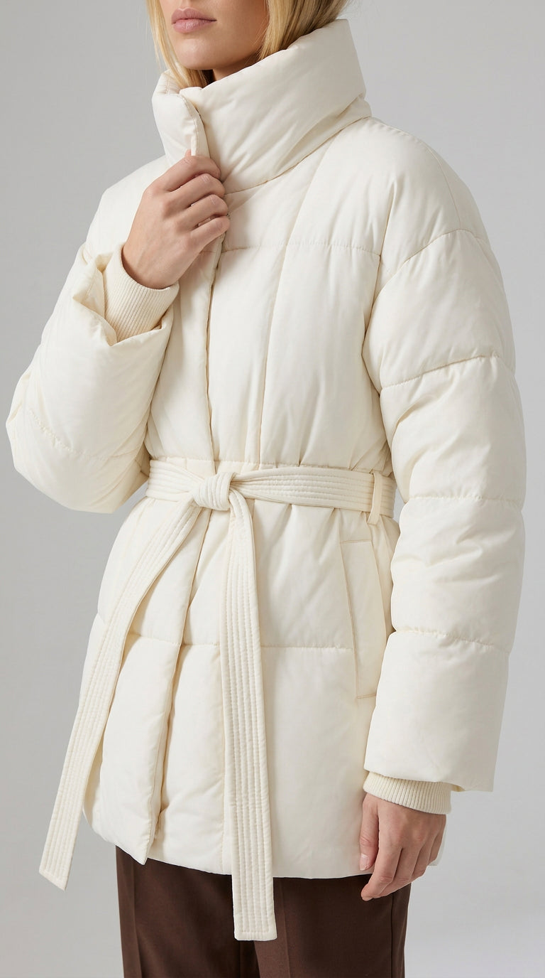 Close-up of the ivory puffer jacket's tall padded collar, ribbed knit cuff and quilted tie belt, ELLA Toronto
